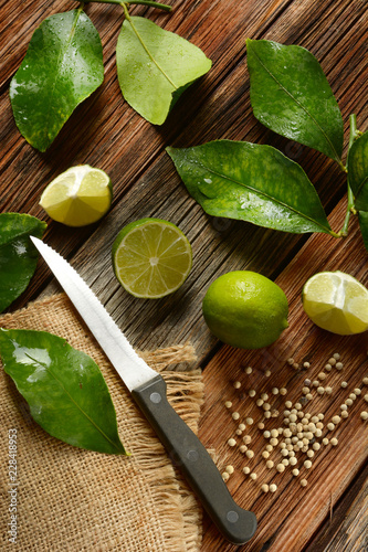 Fototapeta Naklejka Na Ścianę i Meble -  lime fruits with leaves on wooden table - tropical fruit with antioxidant properties