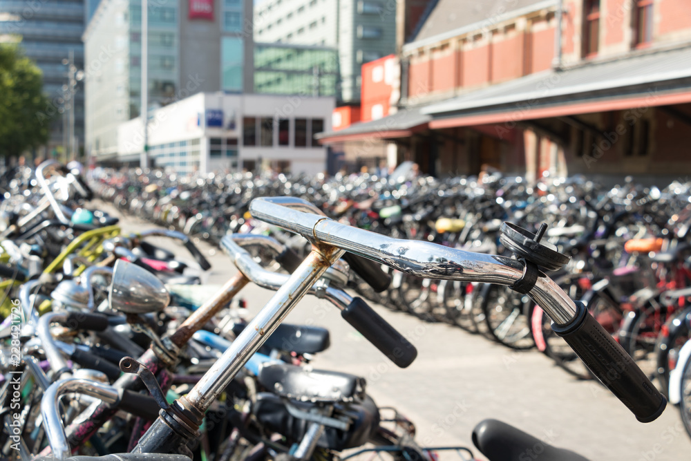 A handlebar of a bike parked with hundred of bicycles in Amsterdam.