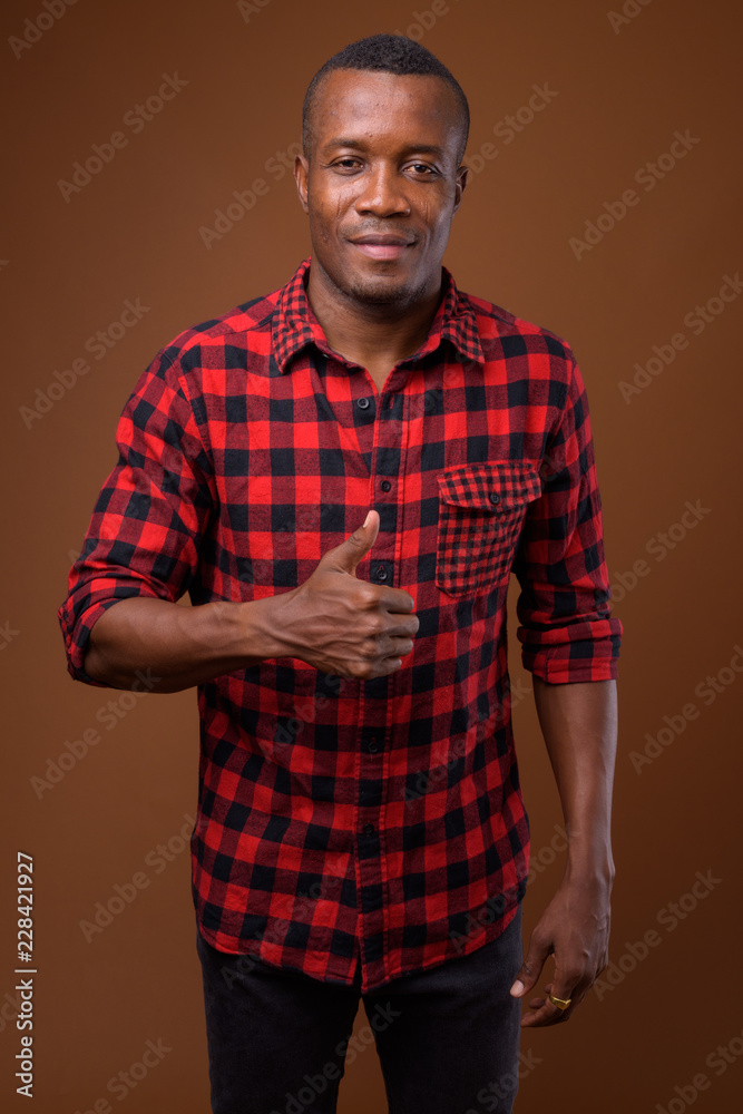 Studio shot of young African man against brown background Studio shot of young African man against brown background