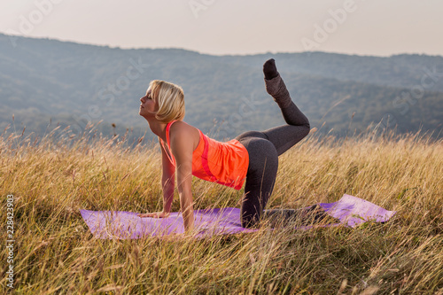 Beautiful woman doing yoga in the nature,Vyaghrasana/Tiger Pose. photo