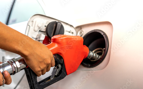 Hand holding gas nozzle in gas station for car refuelling