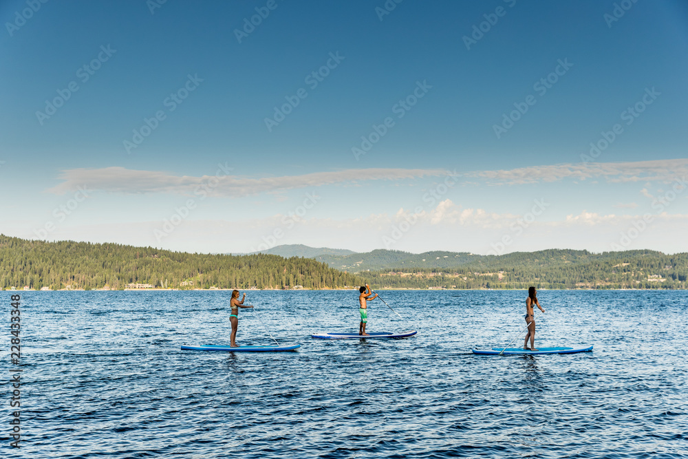 Friends paddle board at lake. 