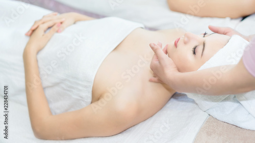 Woman lying in bed relaxing in spa.Woman is lying on the spa bed to do a facial scrub.Spa facial massage in beauty salon.