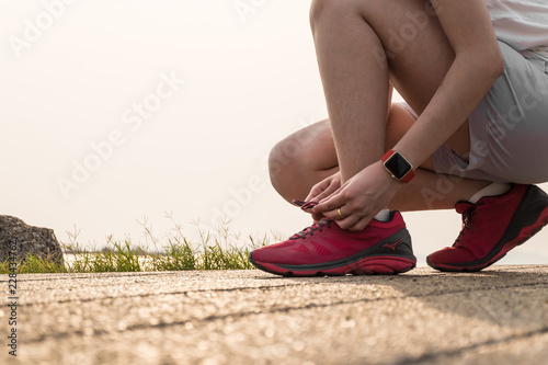 Woman wear smart watch on hand tying running shoes in concept of sport, workout, runing