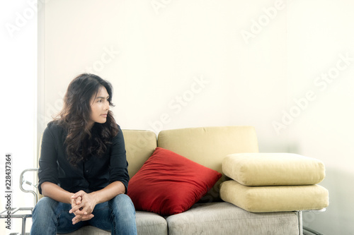 Depressed young woman near window at home, 