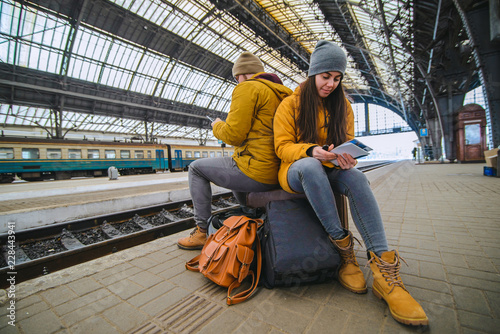 couple sit on valise at railway station Fototapeta
