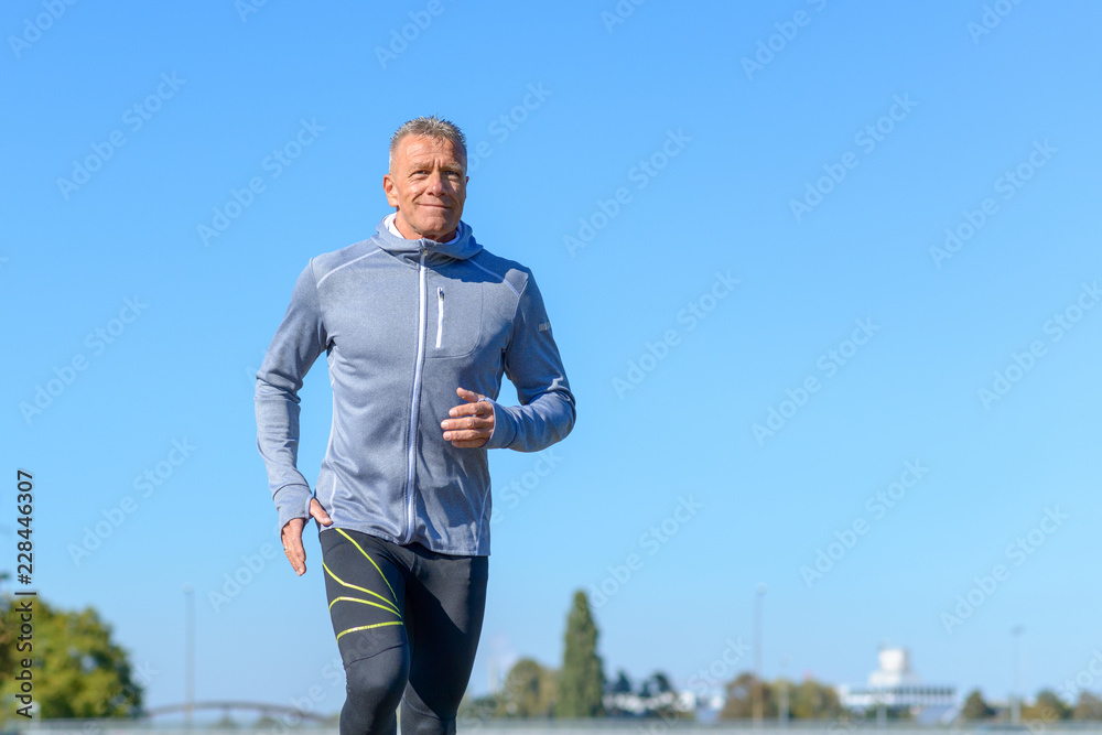 Gray smiling man running through a park Gray smiling man running through a park