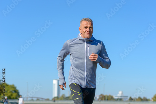 Gray smiling man running along river