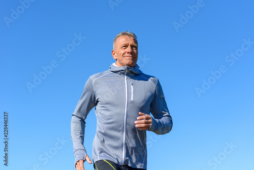 Obraz na płótnie Gray smiling man running through a park