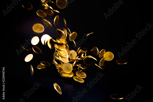 Falling gold coins money in dark background, business concept.