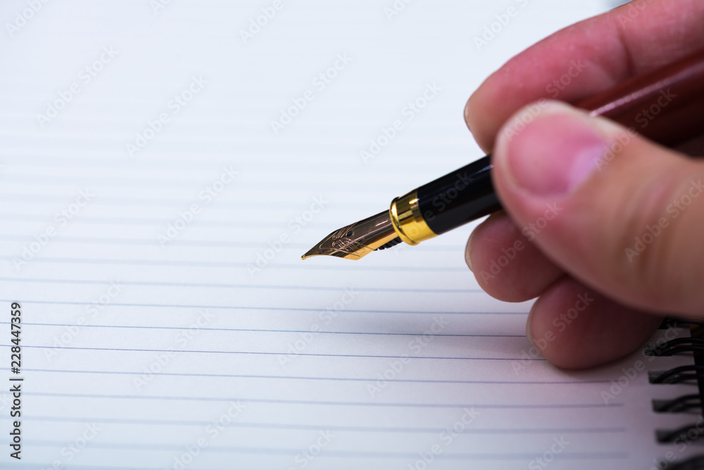 Man hand writing with fountain pen or ink pen with notebook paper on wooden working table with copy space, office desk concept. Man hand writing with fountain pen or ink pen with notebook paper on wooden working table with copy space, office desk concept.