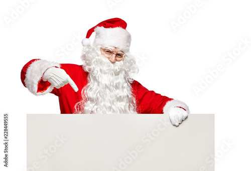 Happy Santa Claus points to a blank banner with to copy space. © k_e_n