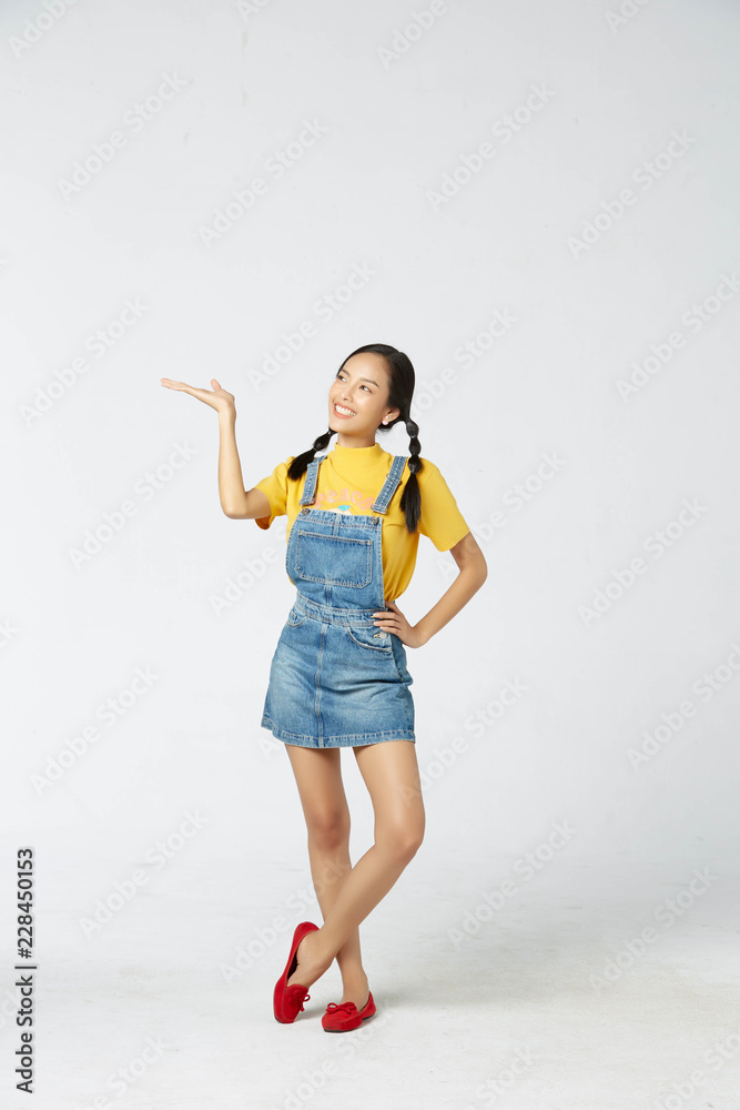 Isolate young tan Asian woman wearing yellow t-shirt, jeans dungarees and expressive facial on white background Isolate young tan Asian woman wearing yellow t-shirt, jeans dungarees and expressive facial on white background