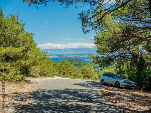 Parked car at top of island Pasman with city Zadar in Croatia in background.