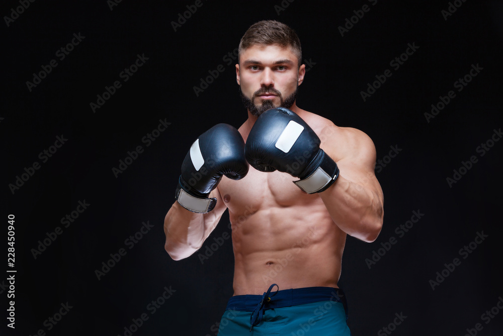 Strong muscular boxer in black boxing gloves. Isolated on black background. Strong muscular boxer in black boxing gloves. Isolated on black background.
