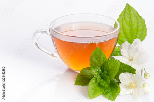 Glass cup of Tea with jasmine flowers and leaves of mint