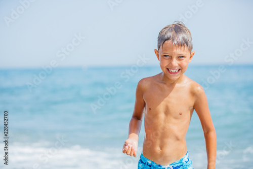 Boy having fun on tropical beach on suuny day photo