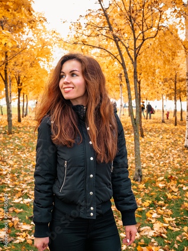 Brunette girl with long hair and jacket standing in autumn yellow forest or Park © KseniaJoyg