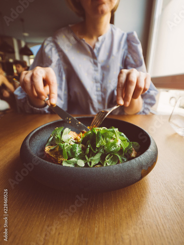 French woman eating delicious green gourmand organic salad in Restaurant using fork and knife - filter vintage photo