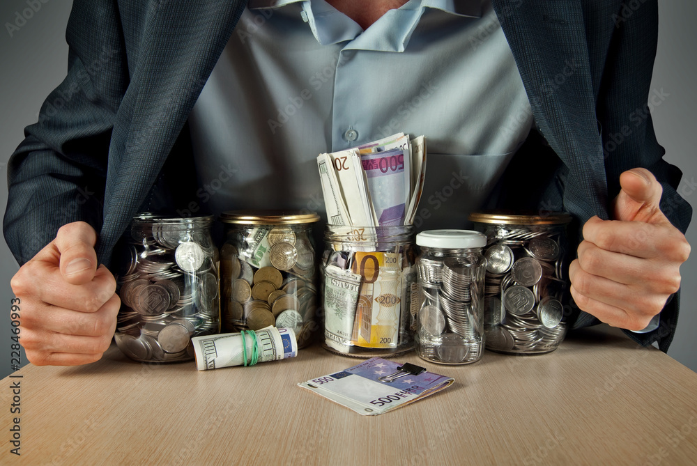 A man in a suit conserved money in glass jars. The concept is the storage of money, stocks at difficult times. Conserve money instead of vegetables.
