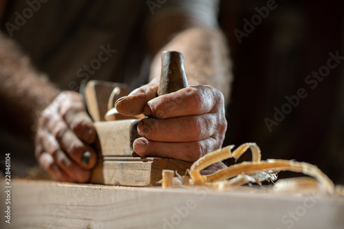 Handwerkerhände mit Holzhobel, Späne liegen auf Holzbalken, selektive Schärfe photo