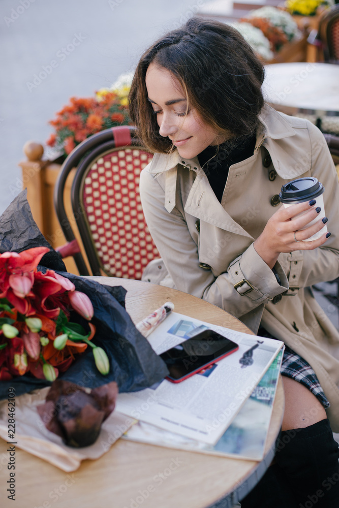 Fototapeta premium Young beautiful woman drinking coffee in a street cafe