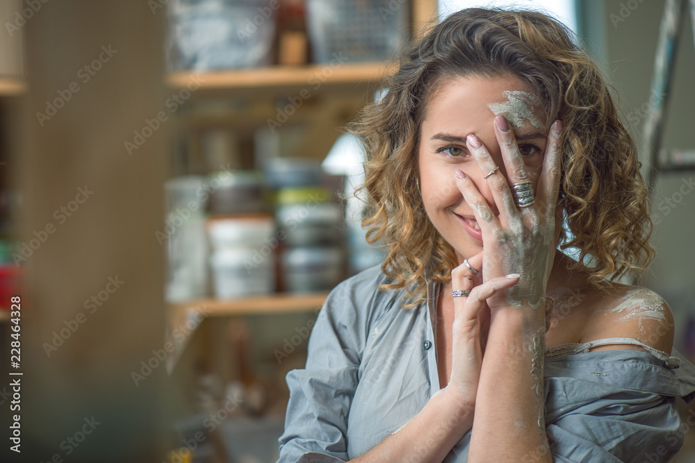 Happy girl stained in clay looks through fingers Happy girl stained in clay looks through fingers