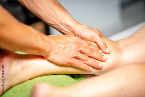 A physiotherapist massaging a woman patient leg at a clinics cabinet