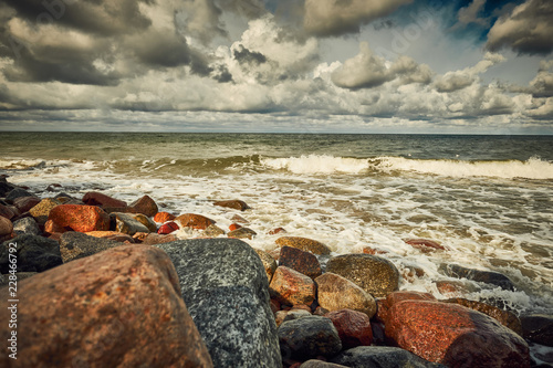 Stones at the beach with wave and nice blue sky with clouds