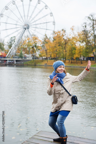 Cheerful young woman dances near a lake in the park