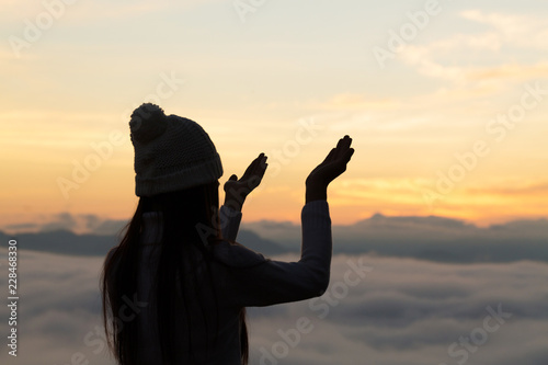 Silhouette off young woman praying for God's blessings with the power and power of the sacred On the background of sunrise. The concept of God and spirituality.
