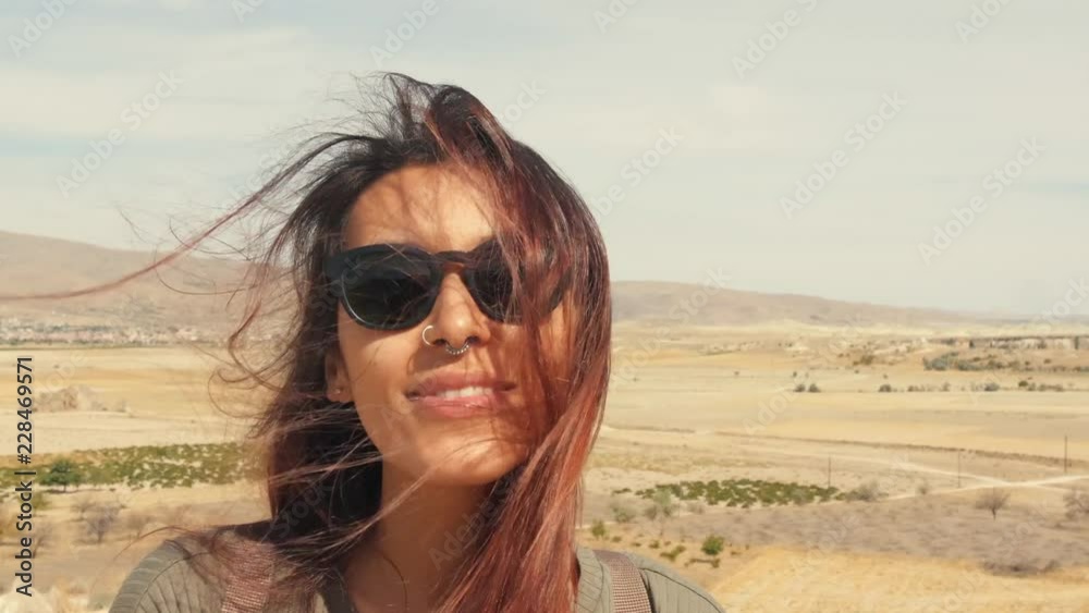 Young Attractive Smiling Mixed Raced Girl Portrait in a Desert. Happy Tourist Woman Posing on Camera with Hair Waving in the Wind. Cappadocia, Turkey. 4K Slowmotion. Young Attractive Smiling Mixed Raced Girl Portrait in a Desert. Happy Tourist Woman Posing on Camera with Hair Waving in the Wind. Cappadocia, Turkey. 4K Slowmotion.
