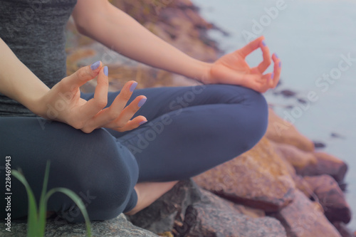 Woman sitting on the rock and meditating in yoga pose