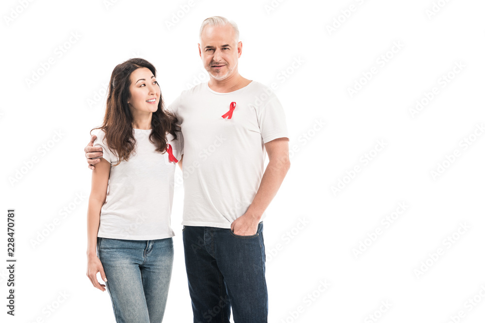happy adult interracial couple in blank t-shirts with aids awareness red ribbons embracing isolated on white