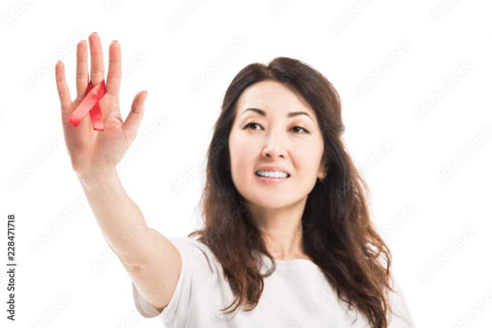 close-up shot of smiling adult asian woman holding aids awareness red ribbon isolated on white