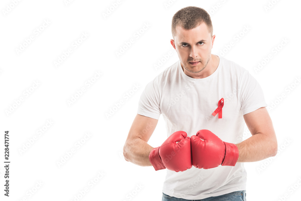 serious handsome man in blank white t-shirt with aids awareness red ribbon and boxing gloves isolated on white, fighting aids concept