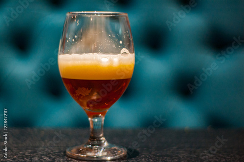 Close up on a glass of amber Pale Ale beer on wooden table in bar with copy space.