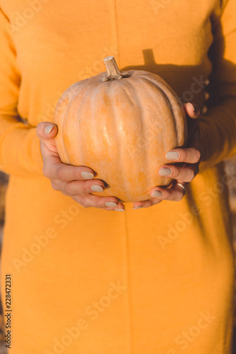 Small orange pumpkin in woman's hands.