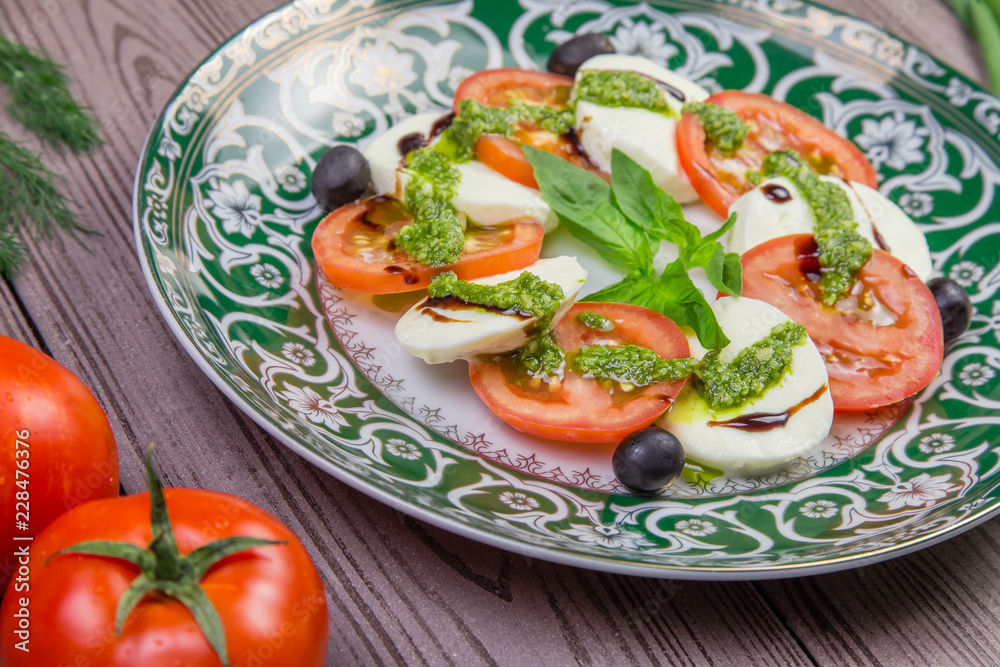 Fresh italian caprese salad with mozzarella and tomatoes on dark plate
