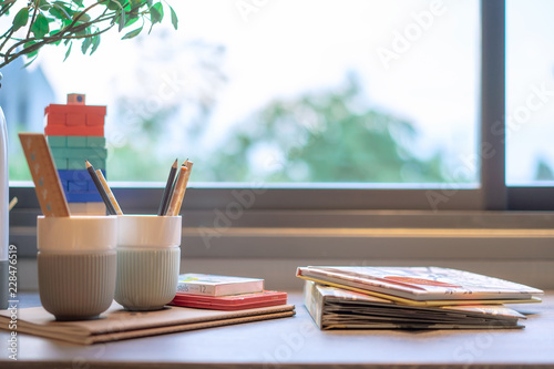 Children's bedroom with pencils and books on the table near the window.