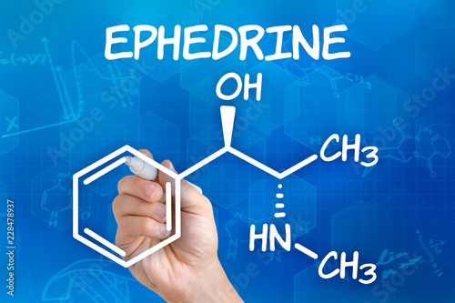 Hand with pen drawing the chemical formula of ephedrine