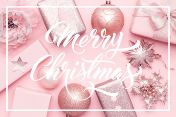 Pink christmas gifts isolated on pastel pink background. Wrapped xmas boxes, christmas ornaments and baubles.