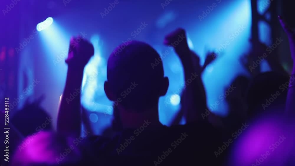 Crowd of people illuminated by colorful light during a concert. Crowd of people illuminated by colorful light during a concert.