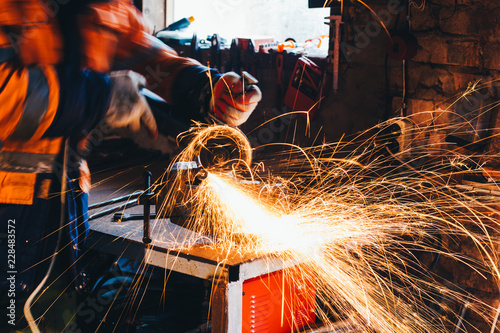 Fotografija Worker cutting metal with grinder in his workshop