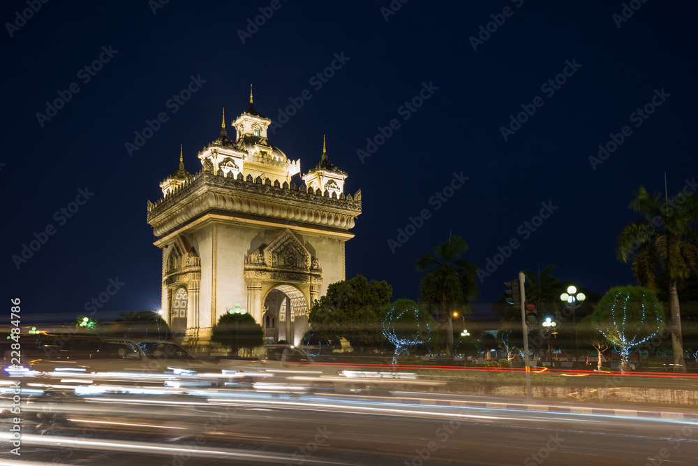 Cars' light trails in front of the lit Patuxai (Patuxay), Victory Gate or Gate of Triumph, war monument in Vientiane, Laos, at dusk.