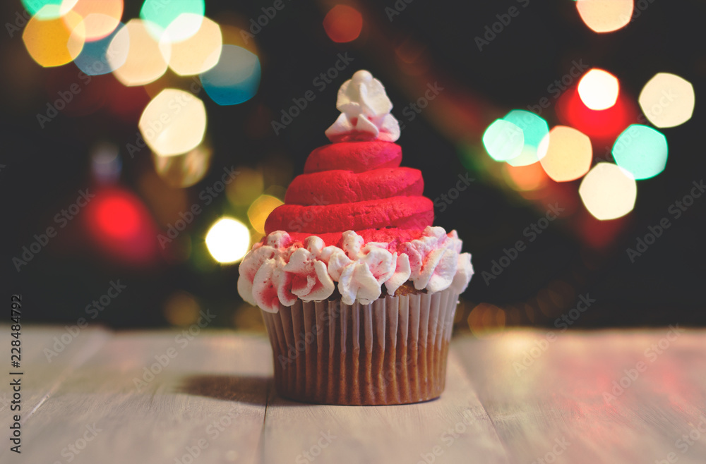 Cupcakes decorated as Santas' hat, for christmas, against colorful bokeh background; holiday background Cupcakes decorated as Santas' hat, for christmas, against colorful bokeh background; holiday background