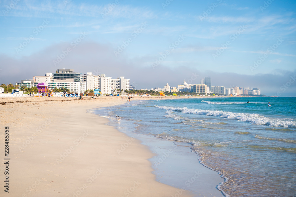 Scenic morning view of waves lapping the shore of an empty South Beach with the city skyline in the background in Miami, Florida, USA