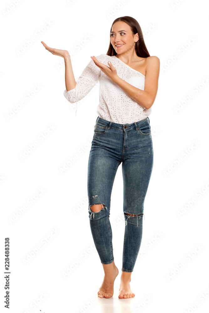 Barefoot young beautiful girl in jeans presenting something on white background Barefoot young beautiful girl in jeans presenting something on white background