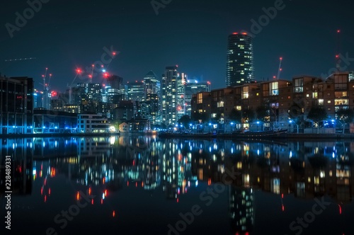 Canary wharf, the financial district of London, UK by night with a reflection in still calm water.