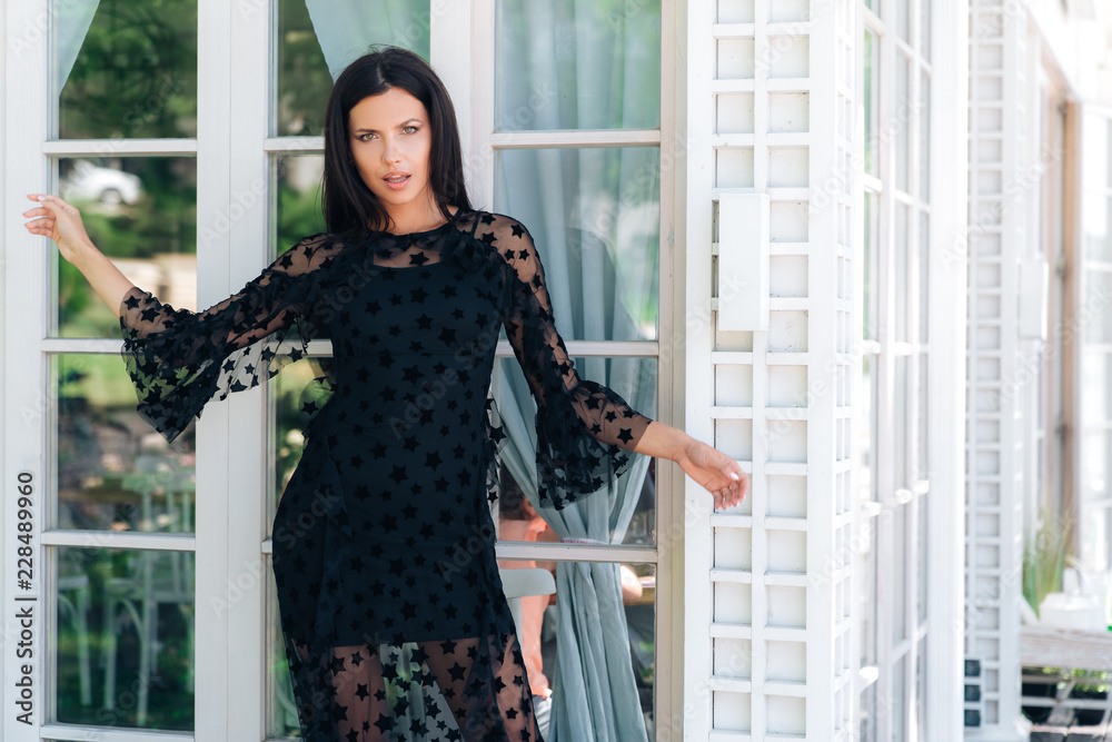 An Attractive Girl is filmed for a fashion magazine. The model put on a long black lace dress, has smooth black hair, plays a playful smile. An Attractive Girl is filmed for a fashion magazine. The model put on a long black lace dress, has smooth black hair, plays a playful smile.